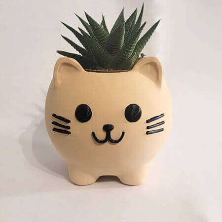Beige cat-shaped 3D printed PLA planter with green succulent, cute minimalist animal design on white background, by Plantale.