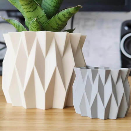 Beige and gray faceted 3D printed PLA planters with geometric diamond design, holding green plant on wooden surface, modern decor by Plantale.