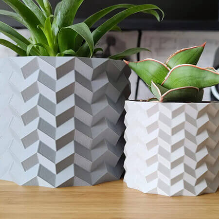 Gray and white geometric 3D printed PLA planters with chevron pattern, holding green succulents, modern minimal tabletop decor by Plantale.
