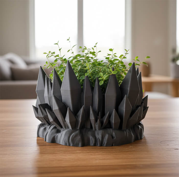 Modern black crystal mountain 3D printed PLA planter with green plant on wooden table indoors.