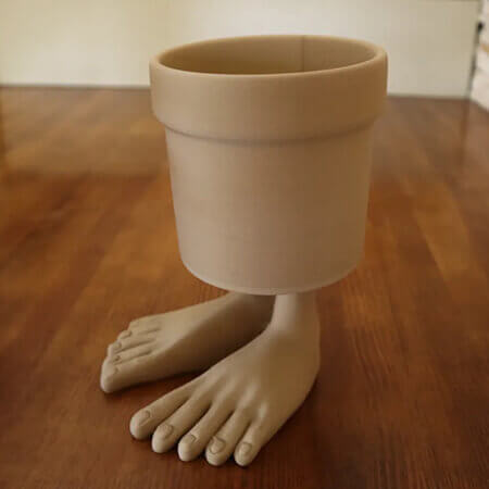 Beige walking feet 3D printed PLA planter featuring realistic human feet base, quirky modern design on wooden surface, by Plantale.