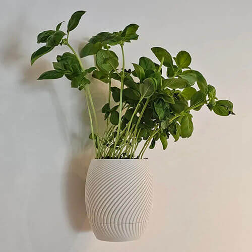White swirl-textured 3D printed hanging wall planter with green indoor plant.