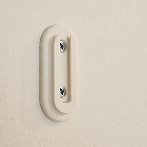 White wall-mounted bracket with two visible screws, designed to hold a hanging planter.