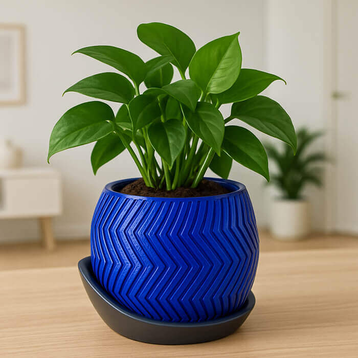 Modern blue chevron 3D printed PLA planter with matching gray tray and green indoor plant on wooden table.