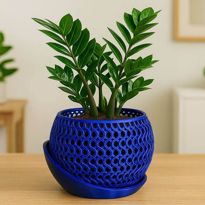 Modern blue wavy mesh 3D printed PLA planter with green indoor plant and matching tray on wooden table.